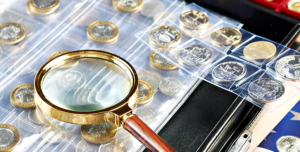 a coin appraiser's magnifying glass rests on a coin collection.al